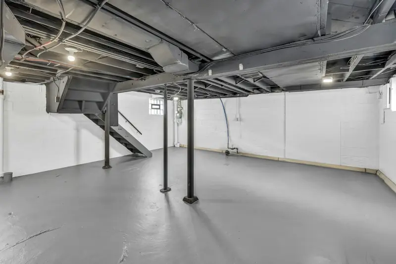 Unfinished basement with exposed joists and support posts